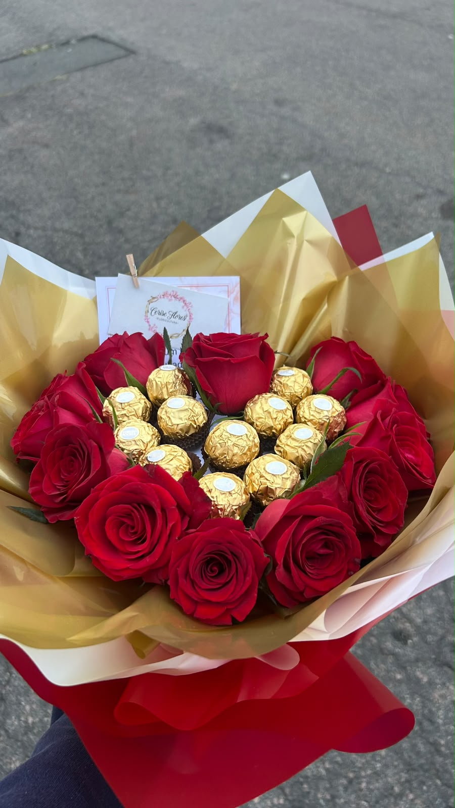 Buquê de rosas vermelhas com bombons Ferrero Rocher ao centro, em papel dourado e vermelho