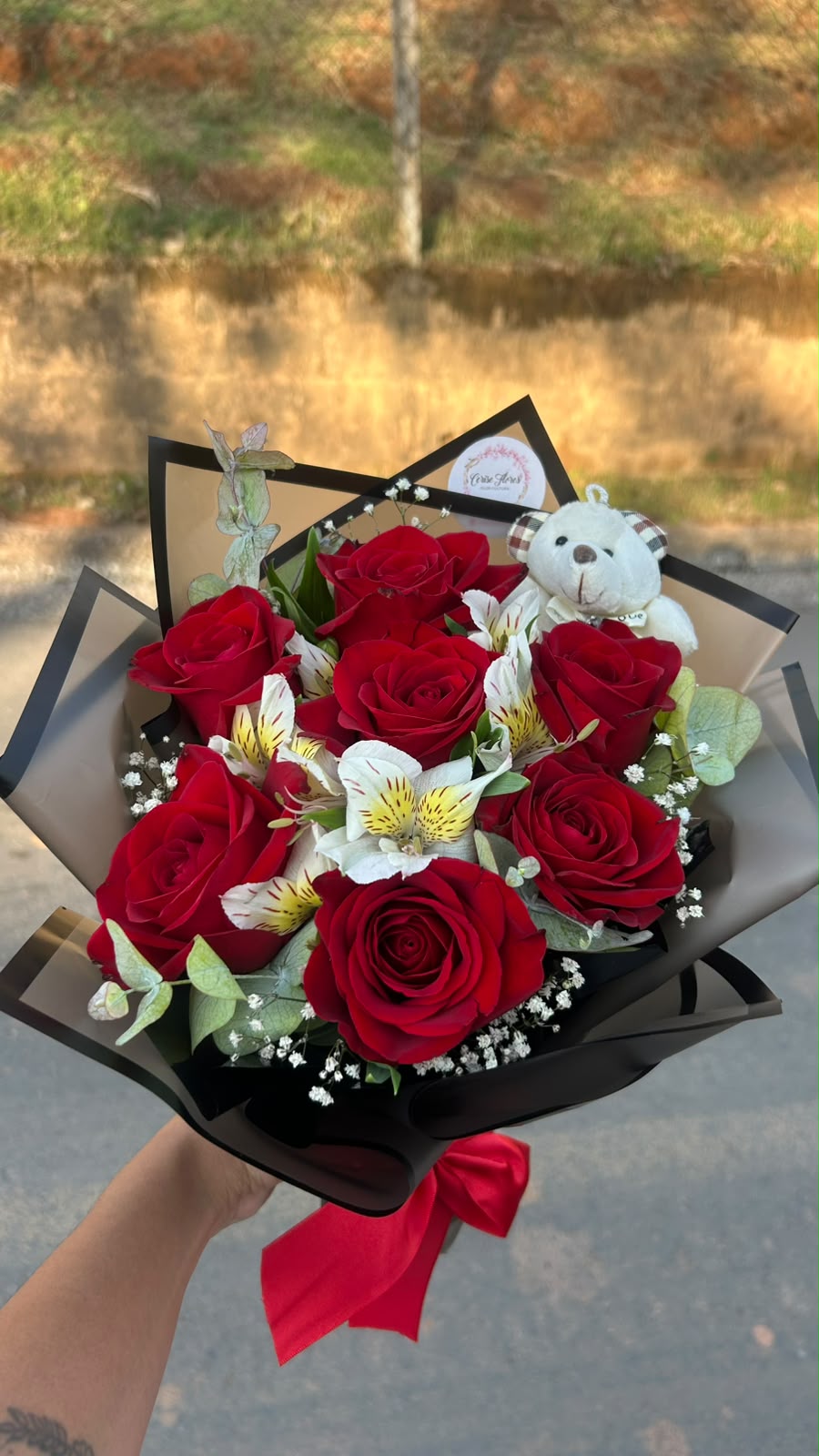 Buquê de rosas vermelhas com alstroemérias, eucalipto e um ursinho de pelúcia, em papel preto