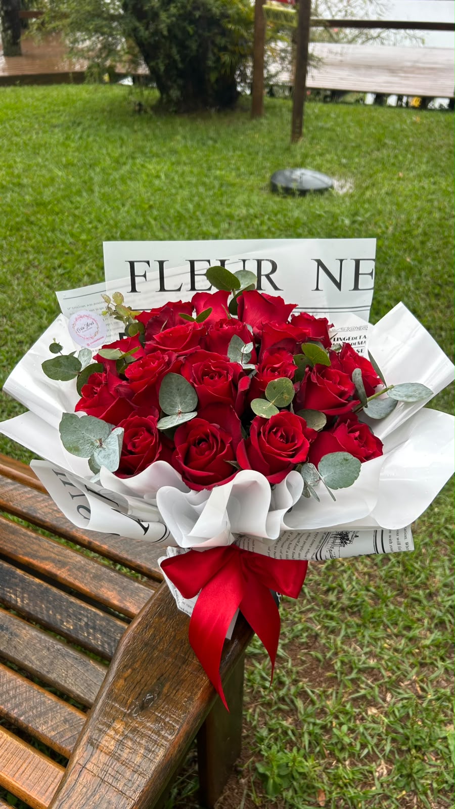 Buquê volumoso de rosas vermelhas com eucalipto em papel estilo jornal e laço vermelho